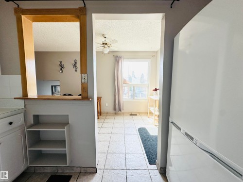 The property features a kitchen with a pass-through window to an adjacent room, white cabinetry, and built-in shelving - 15 Pinecliff Close Ne, Calgary, AB - Indoor Photo Showing Other Room