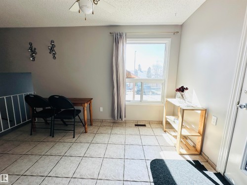 The property features light-colored tiled flooring and a window with white trim - 15 Pinecliff Close Ne, Calgary, AB - Indoor Photo Showing Other Room