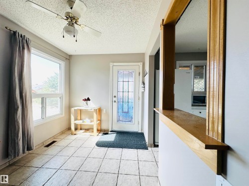 Bright room featuring tiled flooring, a window providing natural light, a ceiling fan, and a door with decorative glass inserts - 15 Pinecliff Close Ne, Calgary, AB - Indoor Photo Showing Other Room