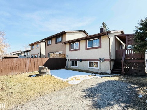The property features a brown wooden fence, a deck with lattice detailing, and a paved driveway - 15 Pinecliff Close Ne, Calgary, AB - Outdoor