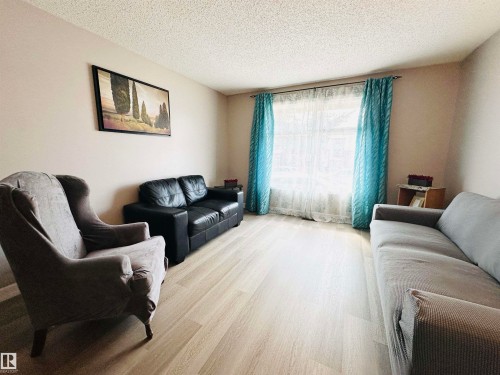 The living room features light-colored flooring, a large window providing natural light, and neutral wall tones - 15 Pinecliff Close Ne, Calgary, AB - Indoor Photo Showing Living Room