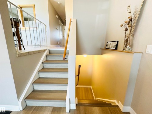 The property features a staircase with light wood-tone treads and white risers, complemented by a light wood-tone handrail - 15 Pinecliff Close Ne, Calgary, AB - Indoor Photo Showing Other Room