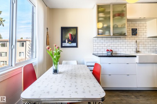 This bright kitchen features white cabinetry, a white subway tile backsplash, and a black countertop - 12 6805 112 Street, Edmonton, AB - Indoor Photo Showing Dining Room