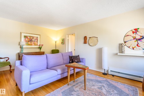 The living space features hardwood floors, light-colored walls, and a textured ceiling - 12 6805 112 Street, Edmonton, AB - Indoor Photo Showing Living Room