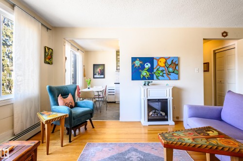 Living area featuring hardwood flooring, a decorative fireplace, and a window with natural light - 12 6805 112 Street, Edmonton, AB - Indoor Photo Showing Living Room With Fireplace
