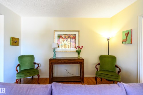 This inviting living space features hardwood floors, light-colored walls, and a corner with a standing lamp providing ambient lighting - 12 6805 112 Street, Edmonton, AB - Indoor Photo Showing Bedroom