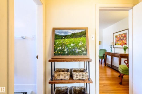 A well-lit hallway featuring light-colored walls and polished hardwood floors - 12 6805 112 Street, Edmonton, AB - Indoor Photo Showing Other Room