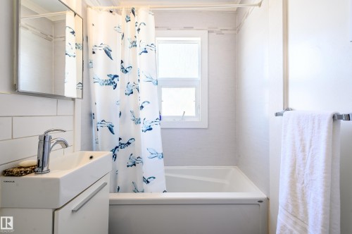 The bathroom features a window for natural light, a bathtub, and a modern vanity with a rectangular sink and chrome faucet - 12 6805 112 Street, Edmonton, AB - Indoor Photo Showing Bathroom