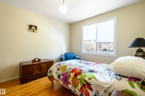 This room features wood flooring, a window with white blinds, and a built-in ceiling light fixture - 12 6805 112 Street, Edmonton, AB - Indoor Photo Showing Bedroom
