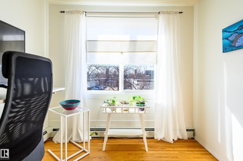 The room features hardwood floors and a window with white blinds and sheer curtains, allowing for natural light - 12 6805 112 Street, Edmonton, AB - Indoor