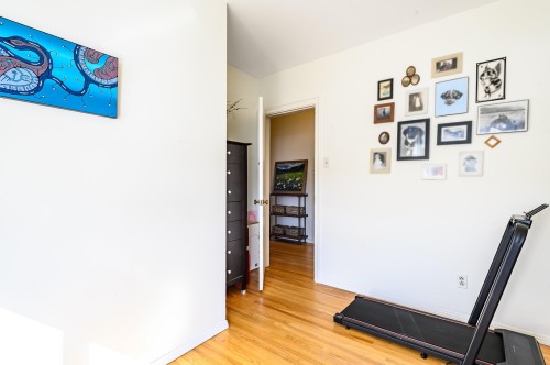 This space features hardwood floors and white walls, offering a versatile area for various uses - 12 6805 112 Street, Edmonton, AB - Indoor