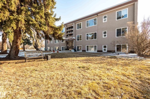 The property features an exterior with a light grey facade, white window frames, and large windows throughout - 12 6805 112 Street, Edmonton, AB - Outdoor
