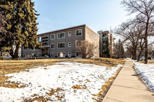 The property features a multi-story exterior with a visible entrance, surrounded by a lawn area and mature trees - 12 6805 112 Street, Edmonton, AB - Outdoor
