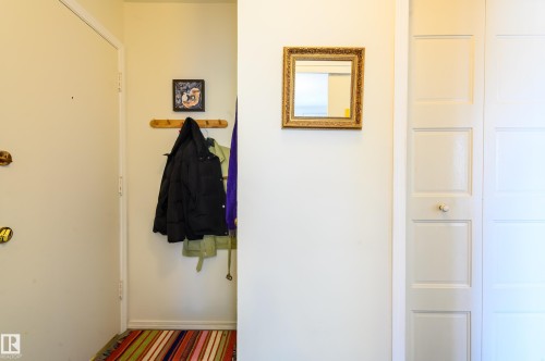 Entryway featuring light-colored walls, a closet with paneled doors, and a decorative mirror - 12 6805 112 Street, Edmonton, AB - Indoor Photo Showing Other Room