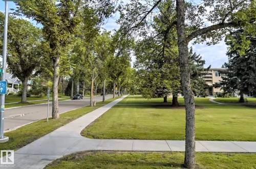 The property is situated in a tree-lined neighbourhood, featuring expansive green spaces and paved sidewalks - 12 6805 112 Street, Edmonton, AB - Outdoor With View
