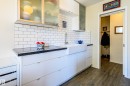 The kitchen features white subway tile backsplash, dark countertops, white cabinetry with a farmhouse sink, and frosted glass upper cabinets - 12 6805 112 Street, Edmonton, AB  - Indoor 