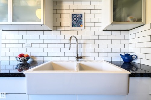 Kitchen featuring a white double basin sink with a chrome faucet, black countertops, and a white subway tile backsplash - 12 6805 112 Street, Edmonton, AB - Indoor Photo Showing Kitchen With Upgraded Kitchen