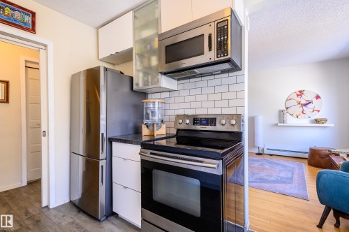 The kitchen features stainless steel appliances, white subway tile backsplash, and dark countertops - 12 6805 112 Street, Edmonton, AB - Indoor Photo Showing Kitchen