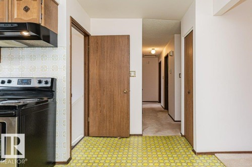 The property features a kitchen with wood cabinetry, a black and stainless steel range, and a patterned yellow floor - 8804 19 Avenue, Edmonton, AB - Indoor Photo Showing Kitchen