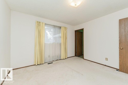 The room features light-colored carpeting, white walls, and a window with curtains - 8804 19 Avenue, Edmonton, AB - Indoor Photo Showing Other Room