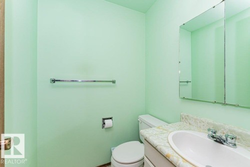 Bathroom with light green walls, a white toilet, and a vanity with a white sink and patterned countertop - 8804 19 Avenue, Edmonton, AB - Indoor Photo Showing Bathroom