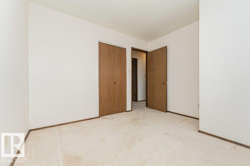 This room features light-colored carpeting, white walls, and wooden bi-fold closet doors - 8804 19 Avenue, Edmonton, AB - Indoor Photo Showing Other Room