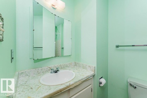The bathroom features a vanity with a countertop and an oval sink, a wall-mounted mirror, and a toilet - 8804 19 Avenue, Edmonton, AB - Indoor Photo Showing Bathroom