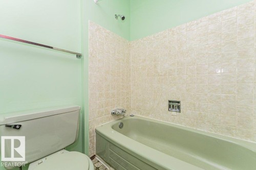 Bathroom featuring a light green bathtub and toilet, with tiled walls above the bathtub and light green painted walls - 8804 19 Avenue, Edmonton, AB - Indoor Photo Showing Bathroom