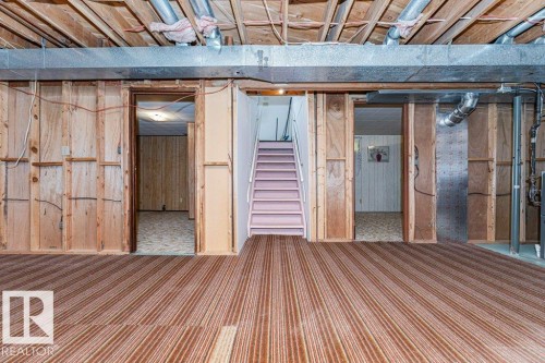 Unfinished basement space with exposed ceiling joists and ductwork, featuring a staircase and carpeted flooring - 8804 19 Avenue, Edmonton, AB - Indoor Photo Showing Basement