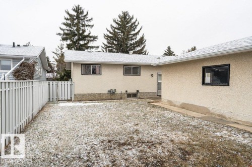 The property features an exterior with light-colored stucco and black-framed windows, complemented by a white picket fence - 8804 19 Avenue, Edmonton, AB - Outdoor