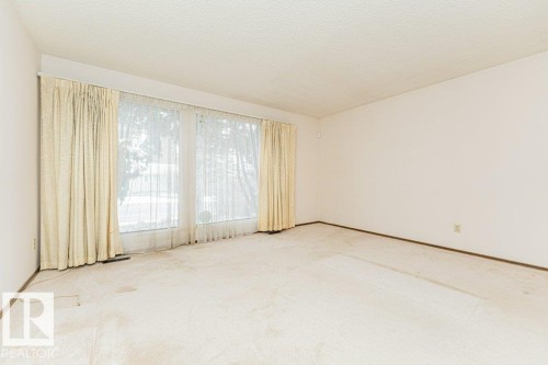 This room features a large window with sheer and opaque curtains, providing ample natural light - 8804 19 Avenue, Edmonton, AB - Indoor Photo Showing Other Room