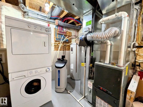Utility area featuring a stacked washer and dryer, water heater, water softener, and furnace - 225 51A Street, Edmonton, AB - Indoor Photo Showing Laundry Room