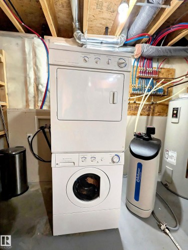 The utility area features a stacked washer and dryer, a water softener, and a water heater - 225 51A Street, Edmonton, AB - Indoor Photo Showing Laundry Room