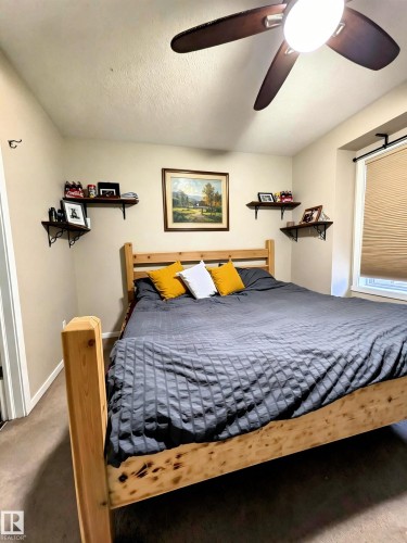 This room features a ceiling fan with integrated lighting, a window with blinds, and wall-mounted shelving - 225 51A Street, Edmonton, AB - Indoor Photo Showing Bedroom