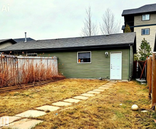 The property features a detached building with green siding and a private entrance, set in a yard with a stone-paver pathway - 225 51A Street, Edmonton, AB - Outdoor With Exterior