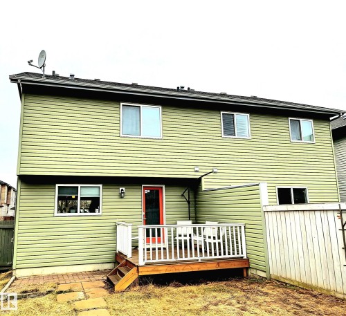 The property features light green siding, a wooden deck with white railings, and a vibrant red back door - 225 51A Street, Edmonton, AB - Outdoor With Exterior