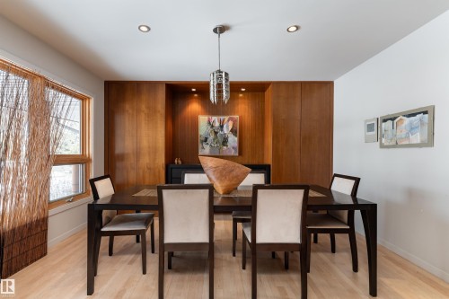 Formal dining area featuring light wood flooring, a window with natural light, and a built-in wooden feature wall with recessed lighting - 9715 141 Street Nw, Edmonton, AB - Indoor Photo Showing Dining Room