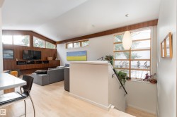 The property features a bright living area with light hardwood floors, a built-in media console, and large windows - 