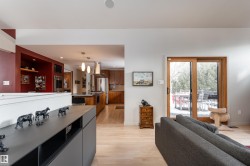 The living area features light-toned hardwood flooring and a large sliding glass door with a wooden frame, providing access to an outdoor space - 