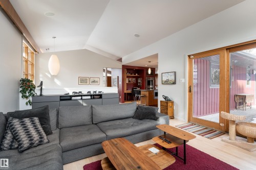 The property features an open-concept living area with light hardwood floors and a vaulted ceiling - 9715 141 Street Nw, Edmonton, AB - Indoor Photo Showing Living Room