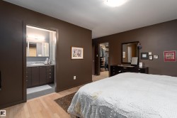 The bedroom features hardwood flooring and direct access to a bathroom with a vanity and mirror, and a walk-in closet - 
