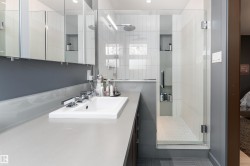 Bathroom featuring a long vanity with an integrated sink, a glass-enclosed shower, and built-in storage niches - 