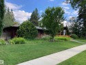 The property features a well-maintained lawn, mature trees, and landscaping with various plantings and flowers - 9715 141 Street Nw, Edmonton, AB  - Outdoor 