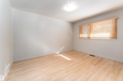 The room features light-colored hardwood flooring, a window with wooden blinds, and a ceiling-mounted light fixture - 