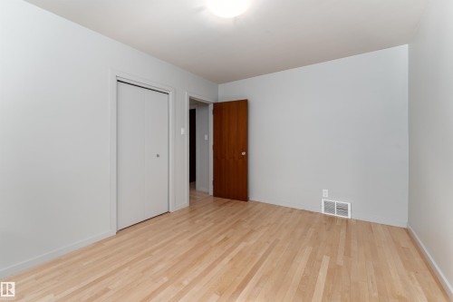 This room features light-colored hardwood flooring, light grey walls, and a white ceiling with a flush-mount light fixture - 9715 141 Street Nw, Edmonton, AB - Indoor Photo Showing Other Room