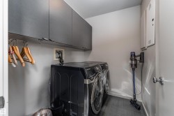 The property features a laundry area with grey cabinetry and a hanging rod - 