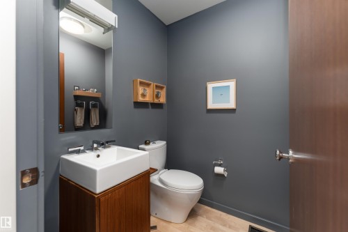 Bathroom featuring a square vessel sink on a wooden vanity, a large wall-mounted mirror, and light wood flooring - 9715 141 Street Nw, Edmonton, AB - Indoor Photo Showing Bathroom