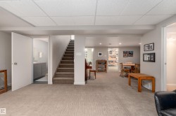 The property features a spacious room with light-colored carpet, a staircase with carpeted treads, and an open doorway leading to a bathroom with a vanity - 