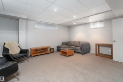 This versatile living space features light grey walls, recessed lighting, and a textured carpeted floor - 