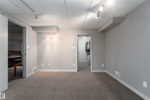 This versatile room features neutral-toned carpet, light gray walls, and recessed lighting, offering a flexible space - 9715 141 Street Nw, Edmonton, AB - Indoor Photo Showing Other Room
